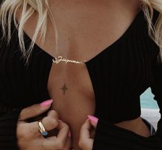 a woman with pink nail polish holding onto her gold ring and wearing a black top