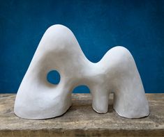 a white sculpture sitting on top of a wooden table next to a blue wall in the background