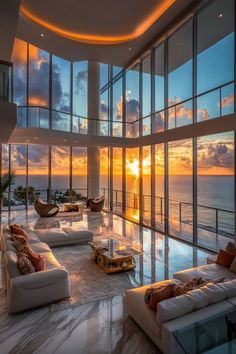 a living room filled with lots of furniture next to an ocean front window at sunset