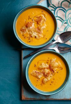 two bowls filled with soup on top of a blue table