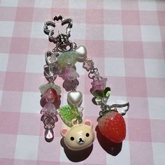 a bear and strawberry charm on a pink checkered table cloth