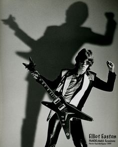 a man holding a guitar in front of a shadow