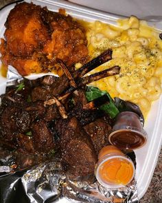 a tray with meat, macaroni and cheese on it