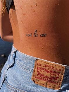 the back of a woman's stomach with words written on it and small holes in her jeans