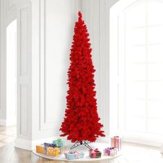 a red christmas tree in the corner of a white room with presents on the floor