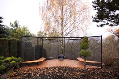 a fenced in area with benches and trees