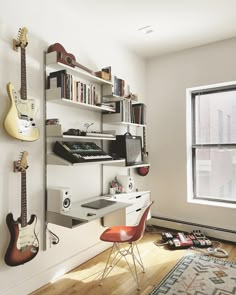 a room with guitars, bookshelves and other musical instruments on the wall next to a window