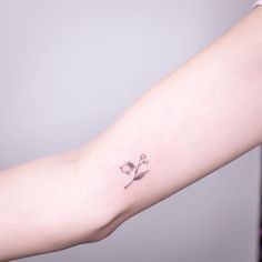 a woman's arm with a small flower tattoo on the left side of her arm