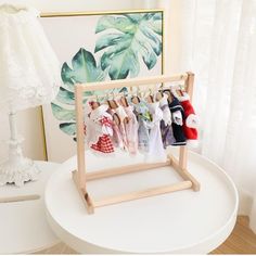 a wooden rack holding baby's clothes on a white table next to a lamp