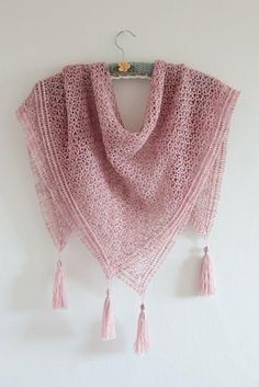 a pink shawl with tassels hanging on the wall