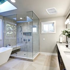 a large bathroom with a walk in shower next to a bathtub and sink under a skylight