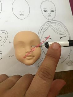 a hand holding a pen over a drawing of a mannequin's head