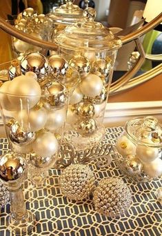 a table topped with lots of glass vases filled with christmas balls and baubles