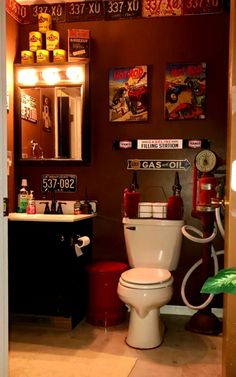 a bathroom with a toilet, sink and various posters on the wall above it's door