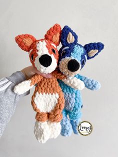 two crocheted stuffed animals are being held by someone's hand in the air