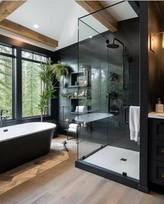 a black and white bathroom with a large bathtub next to a window that looks out onto the woods