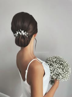 a woman wearing a white dress holding a bouquet of flowers in her left hand and the back of her head