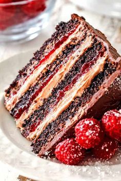 a slice of chocolate cake on a plate with raspberries