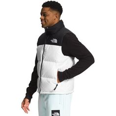 Inspired by The North Face's 1996 Nuptse, the 1996 Retro Nuptse Vest brings throwback style to our look and is versatile enough for our adventures around the city or on the trail. Its lofty goose down insulation traps your body heat for reliable warmth on cold winter days, and the durable face fabric is water-resistant to keep you dry if flakes start to fall. The hood protects your face from the wind, but can be easily stowed into the collar when the weather is fair, while an adjustable hem Casual White Hiking Outerwear, Casual White Outerwear For Hiking, Sporty White The North Face Outerwear, White Sporty Outerwear By The North Face, North Face 1996 Nuptse, Nuptse Vest, The North Face 1996 Retro Nuptse, The North Face 1996, North Face 1996