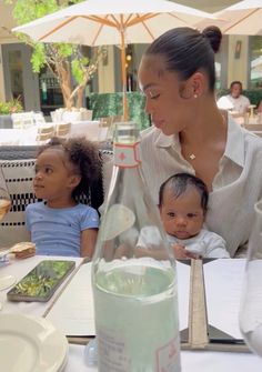 a woman sitting at a table with two children