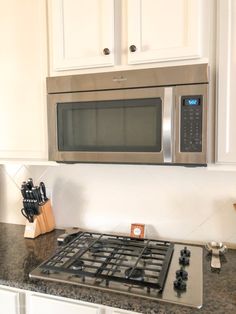 a stove top oven sitting inside of a kitchen next to white cabinets and counter tops