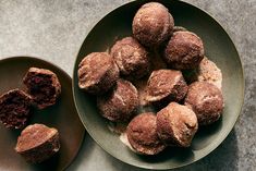 a plate full of chocolate muffins next to a bowl with powdered sugar