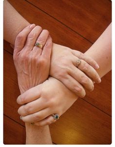 two people holding each other's hands on top of a wooden table