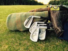 several golf clubs are laid out on the grass in front of a blanket and bag