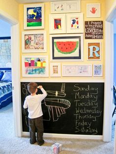 a young boy standing in front of a blackboard with pictures on it