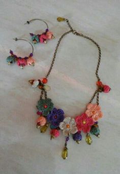 a necklace and earring set made with crochet flowers on a white background