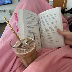 a person is reading a book in bed with a cup of coffee and an umbrella