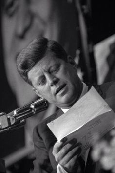 a man holding a piece of paper while standing next to a microphone