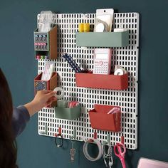 a woman is holding scissors and other items on a pegboard wall mounted to the wall