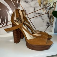 a pair of brown high heeled shoes sitting on top of a white table next to a plant