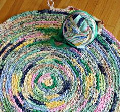 a multicolored rug on the floor with a ball of yarn in the middle