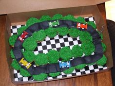 a birthday cake in the shape of a race track with cars on it and grass