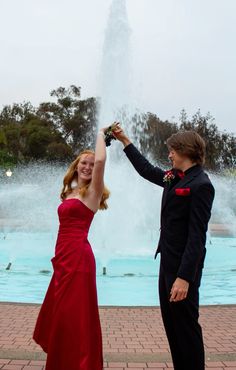 Girl in red prom dress and guy in all black with red bow tie All Black Suit With Red Bow Tie, Black Tux With Red Bow Tie, Red Dress And Black Suit Couple, Black Tux With Red Tie, All Black Suit With Red Tie, Red Dress Grey Suit Prom Couple, Black Suit With Red Bow Tie