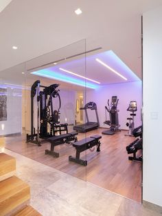 a gym with treadmills, exercise machines and other equipment in the room that is lit up