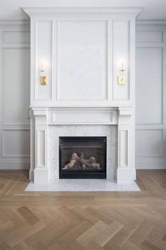 an empty room with a fire place in the center and pictures on the wall above it