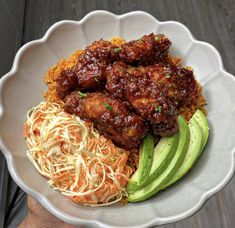 a white bowl filled with meat, rice and veggies next to an avocado