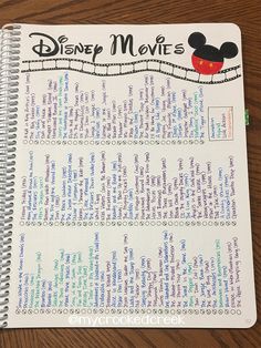 a spiral notebook with the words disney movies written in it on top of a wooden table