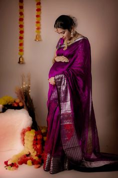 a woman in a purple sari standing next to flowers