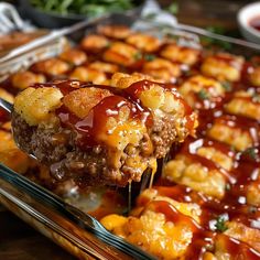 a spoon full of tater tots being lifted from a casserole dish