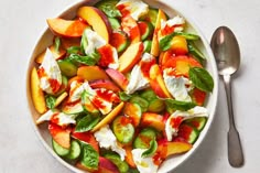 a white bowl filled with sliced peaches, cucumbers and feta cheese