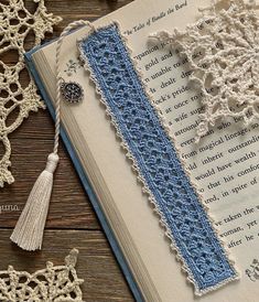 an open book with crocheted lace and tassels on the pages is shown