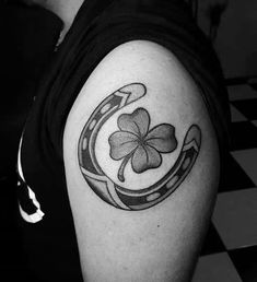 a black and white photo of a shamrock tattoo on the left arm, with a four leaf clover in the center