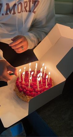 a person lighting candles on a cake in a box