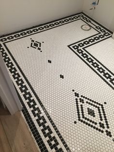 a bathroom with black and white tiles on the floor, shower head in the corner