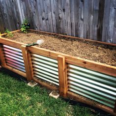 a wooden planter filled with lots of dirt next to a fenced in area