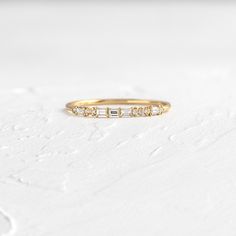 a rose gold ring with three diamonds on the side, sitting on a white surface